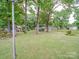 Large grassy backyard featuring mature trees and utility sheds along the fence line at 2213 Milton Rd, Charlotte, NC 28215