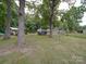 Backyard view showing mature trees and sheds on the property at 2213 Milton Rd, Charlotte, NC 28215