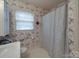 Compact bathroom with floral wallpaper, a window, and a shower with a curtain at 2213 Milton Rd, Charlotte, NC 28215