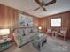 Cozy living room with wood paneling, comfortable seating, and a decorative ceiling fan at 2213 Milton Rd, Charlotte, NC 28215
