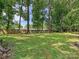 Large, grassy backyard with mature trees and a wooden fence providing privacy and space at 2437 Woodleigh Dr, Gastonia, NC 28056