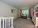 Well-lit room features a crib, soft carpet, and window views, creating a functional and inviting space at 2437 Woodleigh Dr, Gastonia, NC 28056