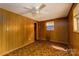 A vintage bedroom featuring wood paneling, patterned carpet, and a ceiling fan at 2871 Loviee Rd, Lincolnton, NC 28092