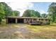 A brick home with a covered area and a wooden deck featuring lush greenery and blue skies at 2871 Loviee Rd, Lincolnton, NC 28092