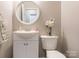 Neat half bath showcasing a pedestal sink with vanity, round mirror and decorative accents at 3626 Cole Mill Rd, Charlotte, NC 28270