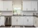 A well-lit kitchen featuring white cabinets, a stainless steel dishwasher, and a subway tile backsplash at 3626 Cole Mill Rd, Charlotte, NC 28270