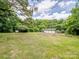 Backyard with storage building surrounded by trees and green grass at 4325 Wolf Pond Rd, Monroe, NC 28112
