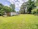 Spacious backyard featuring an outbuilding surrounded by green grass and trees at 4325 Wolf Pond Rd, Monroe, NC 28112