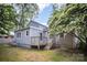 Gray home's backyard showcasing a wooden deck, lush lawn, and the surrounding mature trees at 5421 Princess St, Charlotte, NC 28269