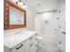 A bathroom featuring a tub, decorative mirror, white cabinets, and patterned floors at 5421 Princess St, Charlotte, NC 28269