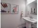 Modern powder room featuring a pedestal sink, decorative mirror, and stylish wall art at 5918 Barrowlands Ct, Charlotte, NC 28210