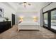 Bright primary bedroom with a tray ceiling, neutral tones, balcony access, and carpet floors at 6990 Ridgeway Rd, Stanley, NC 28164