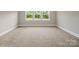 Bright bedroom featuring neutral walls, plush carpeting, and a window overlooking a scenic outdoor landscape at 709 Cavesson Way, Monroe, NC 28110