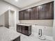 Functional laundry room with dark wood cabinets, granite countertops, and ample storage at 709 Cavesson Way, Monroe, NC 28110