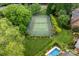 Aerial view of tennis court and pool surrounded by lush landscaping at a luxury home at 7220 Swansea Ln, Cornelius, NC 28031