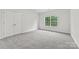 This bedroom has gray carpet flooring, a window and a closet with white double doors at 8505 Loxton Cir, Charlotte, NC 28214