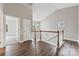 Hallway featuring a wood railing overlooking the staircase, wood floors, and neutral paint at 8505 Loxton Cir, Charlotte, NC 28214