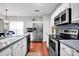 Well-lit kitchen with stainless steel appliances, tile backsplash, white cabinets, and sleek countertops at 8938 Kestral Ridge Dr, Charlotte, NC 28269