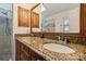 Vanity with dual sinks and granite counter in bathroom with brown cabinets at 9238 Deer Spring Ln, Charlotte, NC 28210