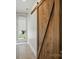 Hallway featuring wood-look flooring, a sliding wooden barn door and backyard access at 945 Westbrook Dr # A, Charlotte, NC 28202