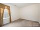 Bedroom featuring neutral carpet, a window with a curtain, and electrical outlets at 10016 Lawing School Rd, Charlotte, NC 28214