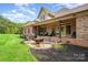 Brick home with covered back porch featuring comfortable outdoor seating, a grill, fire pit, and manicured landscaping at 1010 Nutall Oak Ln, Belmont, NC 28012