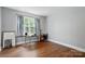Bedroom with hardwood floors, a large window with a guitar and painting at 10431 Plantain Ct, Charlotte, NC 28213