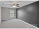 Carpeted bedroom with dark accent wall, ceiling fan, and double windows at 10906 Charmont Pl, Huntersville, NC 28078