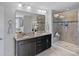 Main bathroom featuring double sinks, granite counters, a large mirror, and tiled walk-in shower at 10906 Charmont Pl, Huntersville, NC 28078