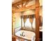 A luxurious bathroom featuring a jacuzzi tub with wooden pillars and a decorative window with patterned curtains at 1140 Fern Hill Rd, Mooresville, NC 28117
