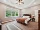 A bright and serene main bedroom with a ceiling fan, a tray ceiling, plush carpeting, and a large window with backyard views at 1140 Fern Hill Rd, Mooresville, NC 28117