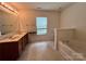 Bathroom featuring a double vanity, soaking tub, and large window for natural light and style at 11505 Sweetbriar Ridge Dr, Charlotte, NC 28269
