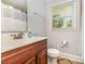 Bathroom featuring a vanity, toilet, mirror, and window to bring in natural light at 1218 E Woodlawn Rd, Charlotte, NC 28209