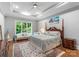 Spacious bedroom with a tray ceiling, hardwood floors, a large bed, and windows overlooking the backyard at 12835 Ninebark Trl, Charlotte, NC 28278