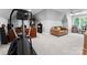 A bonus room with a vaulted ceiling, carpet, a brown sofa, desk, and exercise equipment at 12835 Ninebark Trl, Charlotte, NC 28278