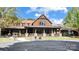 Exterior view of clubhouse featuring a covered porch, stonework, and manicured lawn, offering a welcoming gathering space at 12835 Ninebark Trl, Charlotte, NC 28278