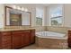 Luxurious bathroom featuring a soaking tub with tiled surround and granite countertops on the vanity at 1400 Delaney Dr, Matthews, NC 28104