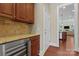 Kitchen area with wine cooler, granite counters, and wood cabinets, leading to a well-lit living space at 1400 Delaney Dr, Matthews, NC 28104