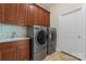 Modern laundry room with wooden cabinets, light backsplash, and gray washer/dryer at 1400 Delaney Dr, Matthews, NC 28104