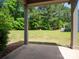 View from covered patio of the grassy backyard surrounded by a natural tree border at 14506 Knowledge Cir, Charlotte, NC 28277