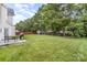 Large backyard with a lush green lawn, mature trees, grill and patio with bench at 15037 Taylor Ridge Ln # 25, Charlotte, NC 28273