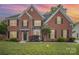 Charming two-story brick home with lush green lawn and meticulously maintained landscaping at sunset at 15037 Taylor Ridge Ln # 25, Charlotte, NC 28273