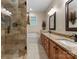 Well-lit bathroom featuring dual sinks, granite countertops, and a tiled shower with glass enclosure at 18846 Cloverstone Cir, Cornelius, NC 28031