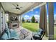 Inviting covered patio featuring a stone fireplace with TV, comfortable seating, and a view of the lush, fenced backyard at 2025 Masons Bend Dr, Fort Mill, SC 29708