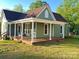 Inviting exterior with expansive porch, classic columns, green siding and a beautiful lawn on a sunny day at 222 Brevard St, Statesville, NC 28677