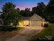 Inviting single-story home with cozy curb appeal at dusk featuring a two-car garage at 3006 Emerald Meadow Ln, Charlotte, NC 28273