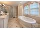 Bright bathroom features a freestanding tub, glass shower, vanity, and large window, offering a luxurious experience at 321 W Bank St, Salisbury, NC 28144