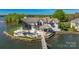 Aerial view of luxurious lake house with pool, dock, and lush landscaping on a private peninsula at 3386 Governors Island Dr, Denver, NC 28037