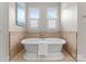 Elegant bathroom featuring a freestanding tub, travertine tile, and bright natural light from two windows at 3815 Stoney Ridge Trl, Charlotte, NC 28210
