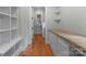 Hallway featuring wooden floors and built-in cabinets and shelves leading to the laundry area at 3815 Stoney Ridge Trl, Charlotte, NC 28210